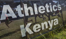 FILE - Junior athletes run past a sign for Athletics Kenya at the Discovery cross country races, an annual race held to identify up-and-coming new young talent, in Eldoret, Kenya on Jan. 31, 2016. Kenya has achieved unparalleled success in modern distance running, but a wave of positive drug tests over the last decade has ruined that reputation, made it the sport's latest doping pariah, and pushed it to the brink of a sweeping international ban that would sit it alongside Russia. (AP Photo/Ben Curtis, File)