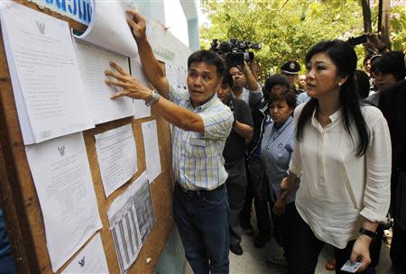 Thai Prime Minister Yingluck Shinawatra (R) checks a list of voters' names before voting at a polling station in Bangkok March 30, 2014. Thais voted on Sunday for half of the country's 150-seat Senate in a key test for Yingluck's troubled government, a day before the prime minister is due to defend herself against negligence charges over a disastrous rice subsidy scheme. REUTERS/Chaiwat Subprasom