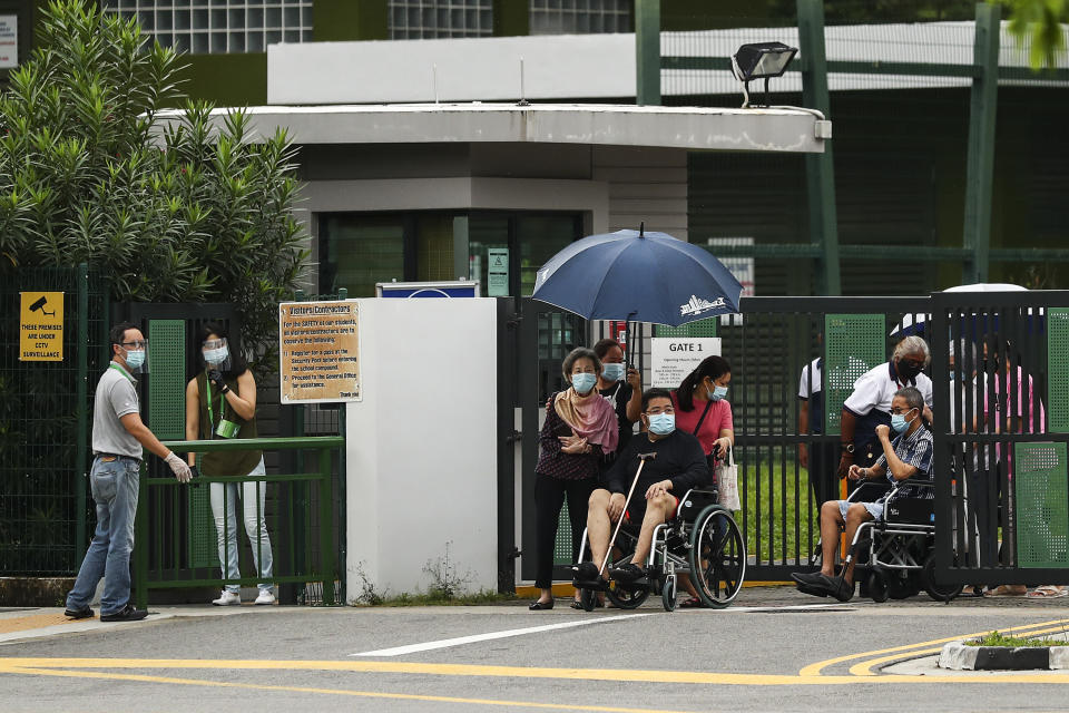 Wheelchair-bound voters, wearing face masks, leave the Alexandra Primary School polling center after casting their votes in Singapore, Friday, July 10, 2020. Wearing masks and plastic gloves, Singaporeans began voting in a general election that is expected to return Prime Minister Lee Hsien Loong's long-governing party to power. (AP Photo)