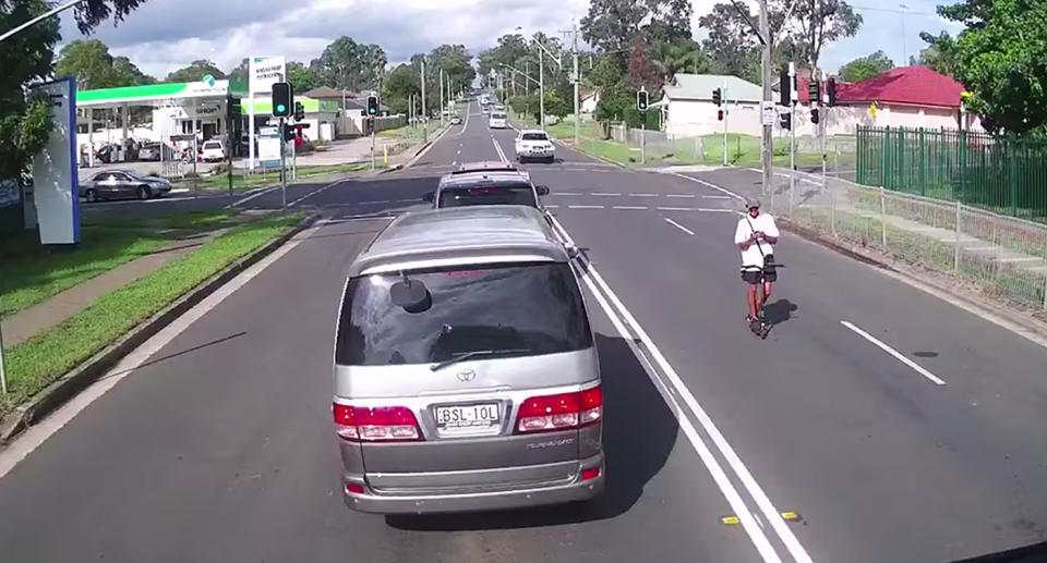 The rider can be seen looking down at his phone as he rides blindly into the next lane of oncoming traffic. Image: Facebook/Dash Cam Owner’s Australia