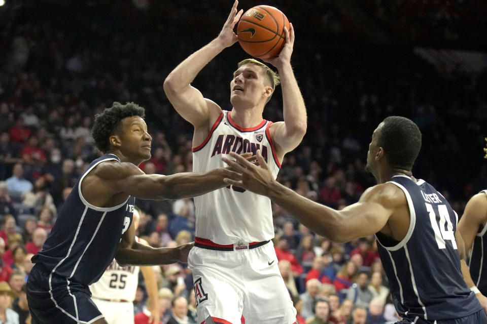 Arizona forward Azuolas Tubelis, center,drives between Utah Tech forwards Trey Edmonds and Dancell Leter (14) during the second half of an NCAA college basketball game, Thursday, Nov. 17, 2022, in Tucson, Ariz. (AP Photo/Rick Scuteri)