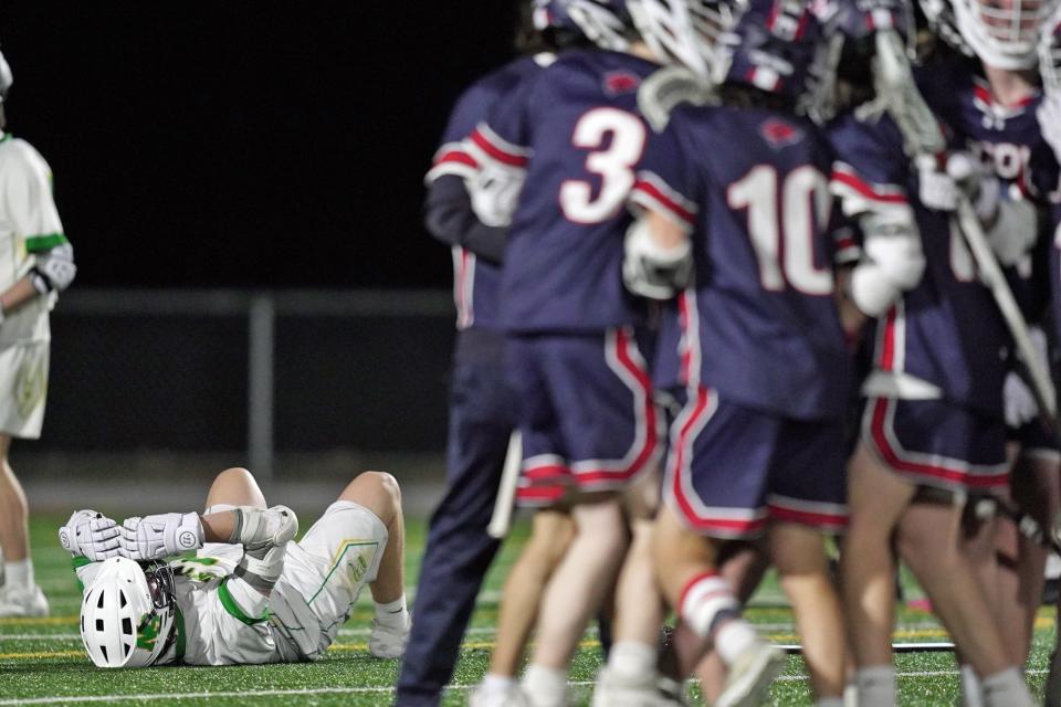 A North Smithfield player reacts as the Lincoln boys lacrosse team celebrates nearby after a goal by Lincoln's Luke Richards in the second overtime that looked like it ended Wednesday's game until the officials said the ball didn't actually go in between the pipes.