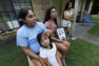 Sisters Kristi Wishork, left, consoles her daughter Renaya Farmer, 5, as she and her sisters Kristina Taylor, center and Kaydee Taylor, right recall the family pride and love their late mother, Sharon Taylor, had for their family, Tuesday, July 21, 2020 outside the family home in Tucker, Miss. Sharon Taylor, 53, died of coronavirus at the University of Mississippi Medical Center in Jackson on June 26 after two weeks in the hospital and never saw her daughter Kristina, the class valedictorian at Choctaw Central High School, graduate. (AP Photo/Rogelio V. Solis)