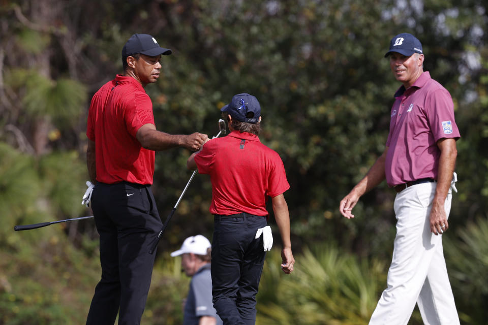 Tiger Woods fist bumps his son Charlie Woods on the the third green during the second round of the PNC Championship golf tournament Sunday, Dec. 19, 2021, in Orlando, Fla. (AP Photo/Scott Audette)