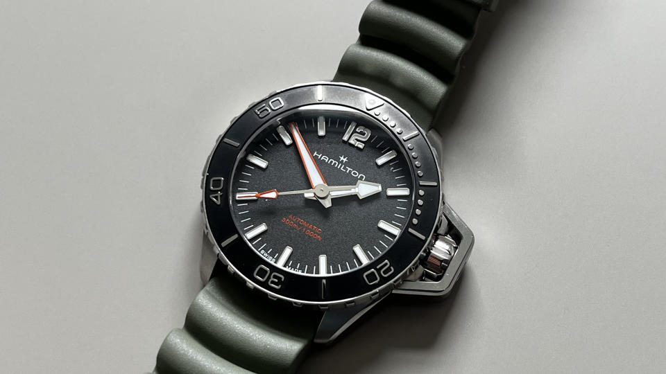 The Hamilton Khaki Navy Frogman with a black dial and a green rubber strap on a grey background