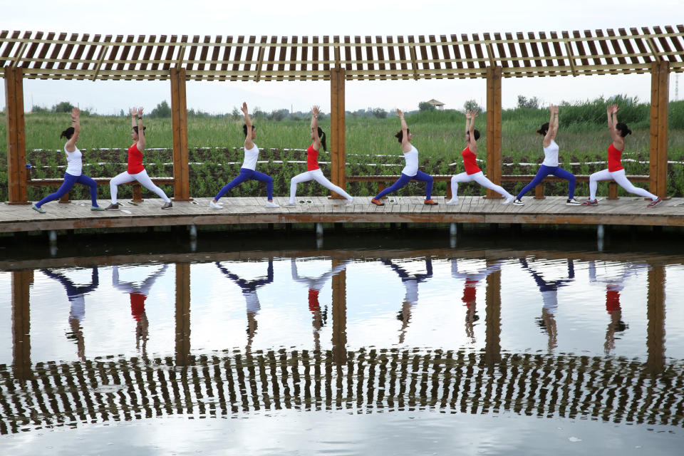 <p>Yoga enthusiasts practice yoga at a wetland park on International Yoga Day, in Zhangye, China, June 21, 2017. (Photo: Stringer/Reuters) </p>