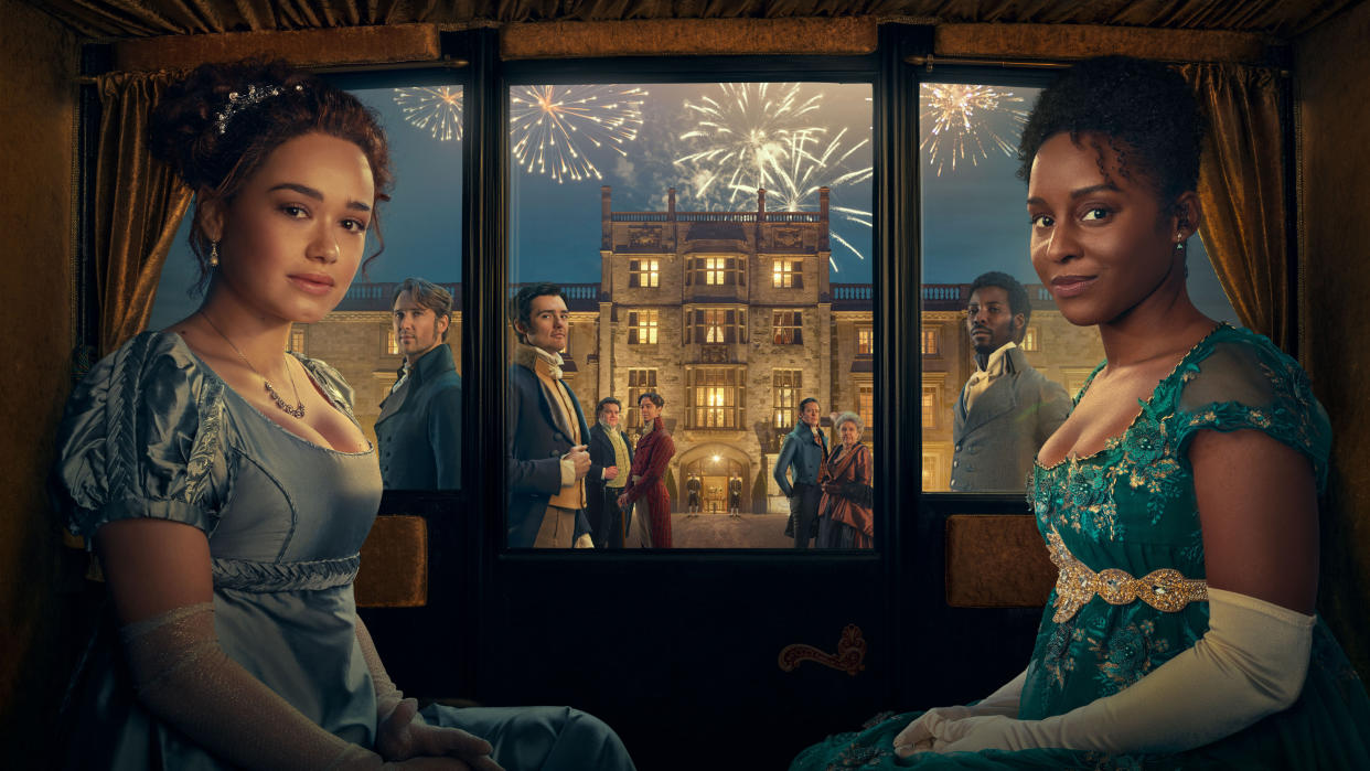  Sanditon's Charlotte (Rose Williams) and Georgiana (Crystal Clarke) are sitting inside a carriage wearing lavish party outfits. Through the windows behind them we can see a stately home with fireworks exploding above, and the characters of Alexander and Samuel Colbourne, Arthur Parker, Edward Montrose, Tom Parker, Lady Denham and Otis Molyneux 