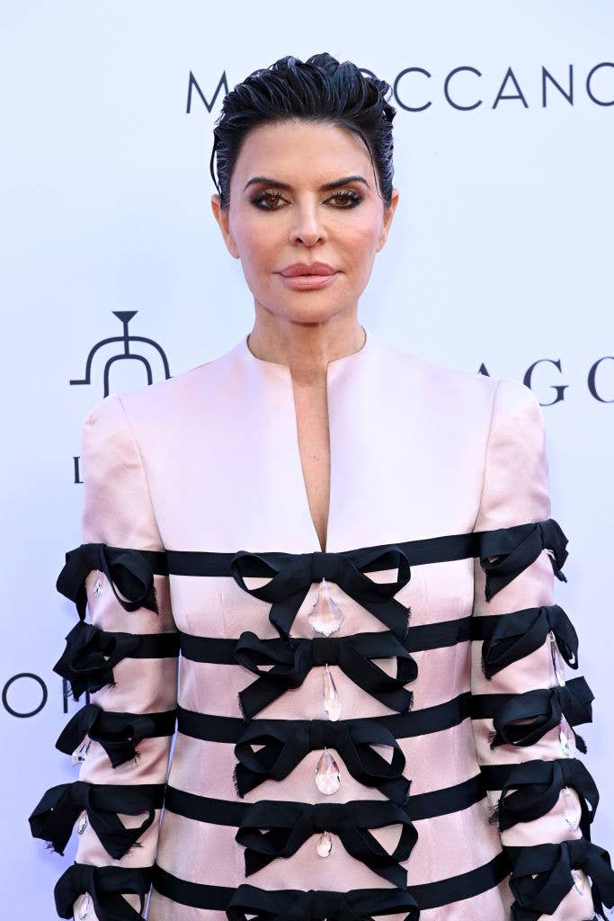 Lisa Rinna on the red carpet in a structured jacket featuring multiple black ribbon details and crystal accents