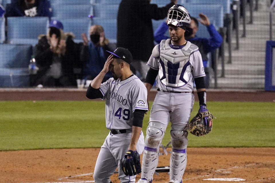 Colorado Rockies starting pitcher Antonio Senzatela, left, wipes his face as catcher Elias Diaz watches after Los Angeles Dodgers' Corey Seager scored on a single by Gavin Lux during the third inning of a baseball game Tuesday, April 13, 2021, in Los Angeles. (AP Photo/Mark J. Terrill)