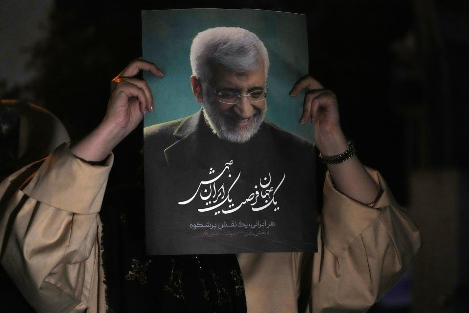 A supporter of Iranian presidential candidate Saeed Jalili holds up a poster of Jalili during his campaign stop in Tehran, Iran, Wednesday, June 26, 2024. (AP Photo/Vahid Salemi)