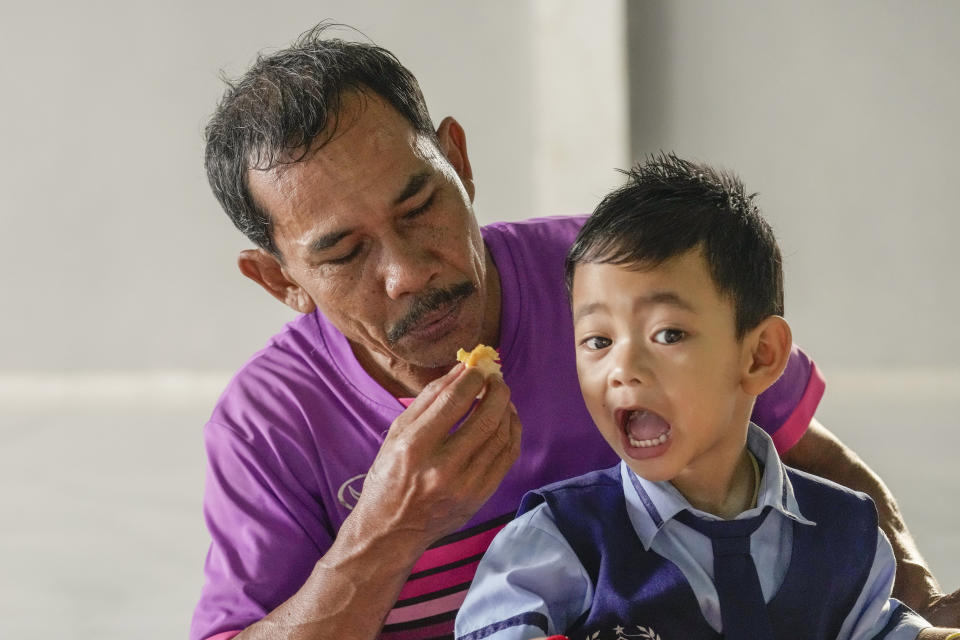 Tawee Lasopha feeds breakfast to his grandson Thanathorn Sopha, son of his daughter Maliwan Lasopha who was killed in a knife and gun attack at The Young Children's Development Center, in the rural town of Uthai Sawan, in Nong Bua Lamphu province, northeastern Thailand, Thursday, Oct. 5, 2023. On Friday, Oct. 6, Tawee marks the first anniversary of the death of his daughter Maliwan Lasopha. (AP Photo/Sakchai Lalit)