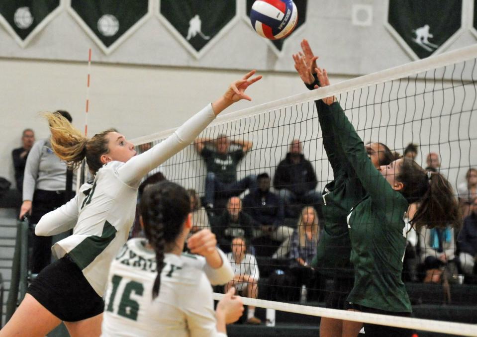 Duxbury's Skye Cerow, left, spikes over Dartmouth defenders during girls volleyball action at Duxbury High School, Monday, Oct. 24, 2022.