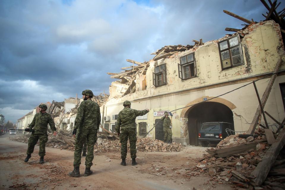 Croatian soldiers stand next wreckage and damaged buildings in Petrinja, some 50kms from Zagreb, after the town was hit by an earthquake of the magnitude of 6,4 on December 29, 2020. - The tremor, one of the strongest to rock Croatia in recent years, collapsed rooftops in Petrinja, home to some 20,000 people, and left the streets strewn with bricks and other debris. Rescue workers and the army were deployed to search for trapped residents, as a girl was reported dead. (Photo by Damir SENCAR / AFP) (Photo by DAMIR SENCAR/AFP via Getty Images)