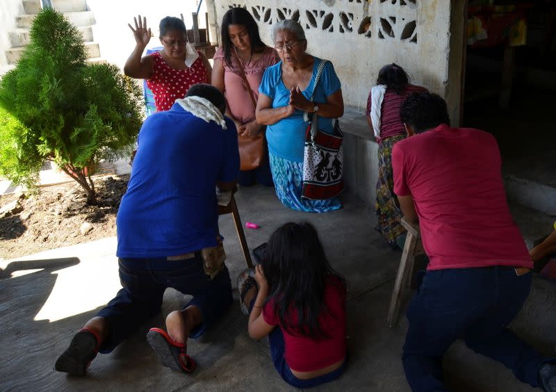 Friends pray in the home of Gerardo Zacarias and his wife Maria Victoria Orozco, who fear their daughter Paola Damaris is among the 19 bodies found shot and burnt in a remote part of northern Mexico, in Catarina