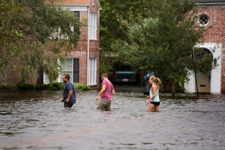 People wade through the flooded streets of the San Marco historic district of Jacksonville, Florida