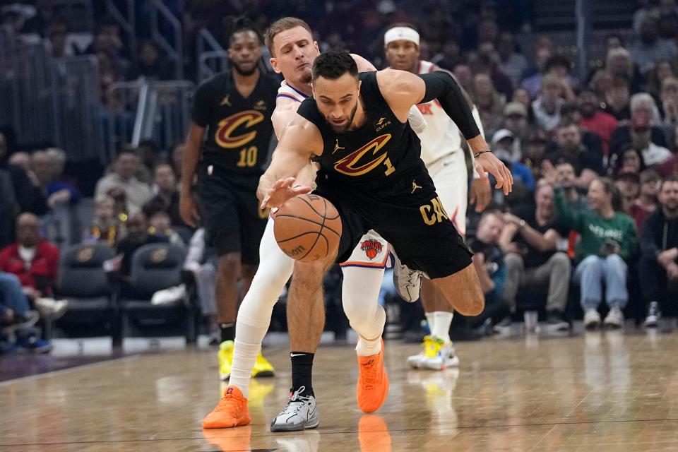 New York Knicks guard Donte DiVincenzo, left, fouls Cleveland Cavaliers guard Max Strus (1) in the first half of an NBA basketball game, Sunday, March 3, 2024, in Cleveland. (AP Photo/Sue Ogrocki)