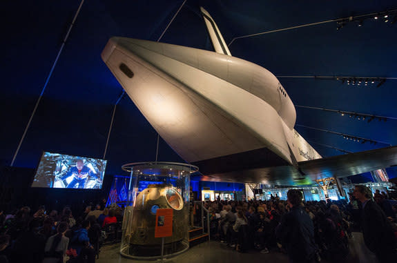 NASA astronaut Scott Kelly (on screen) delivers a message from onboard the International Space Station during the dedication of the space shuttle Enterprise at the Intrepid Museum in New York City.