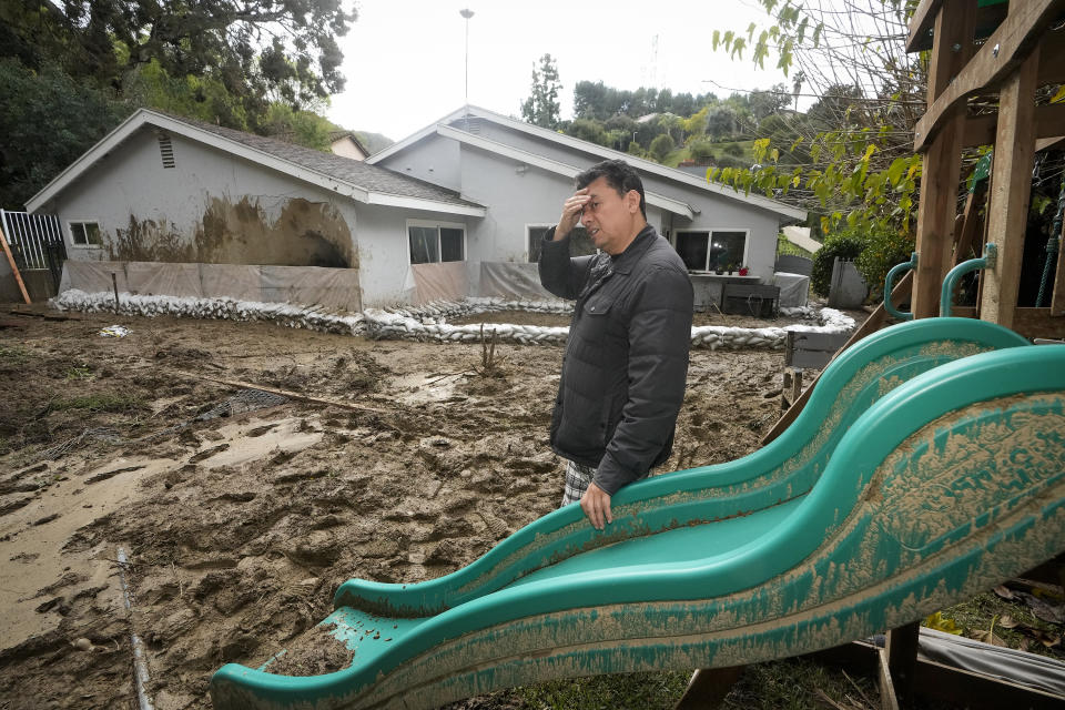 Jesus Barron looks at the damage, created by a mudslide, in his backyard, Wednesday, Feb. 7, 2024, in Hacienda Heights, Calif. (AP Photo/Damian Dovarganes)