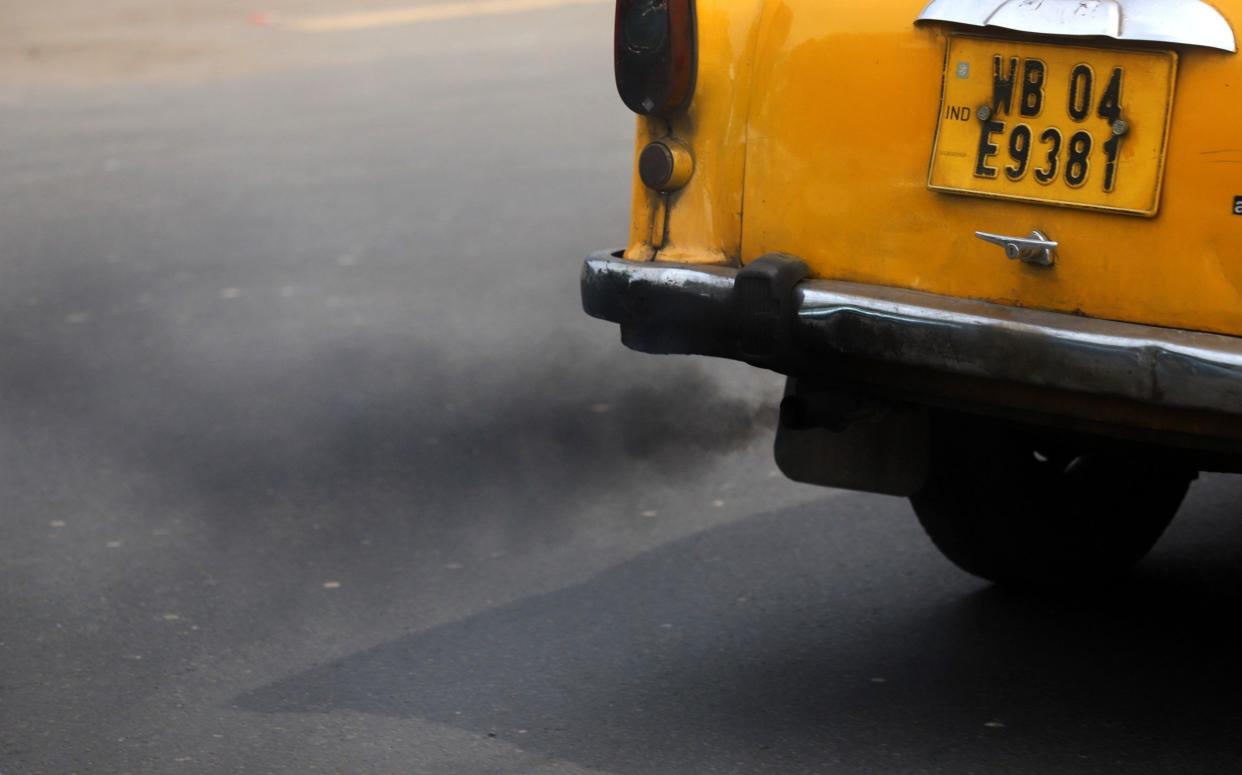 A private cab emits smoke in a street in Kolkata, India