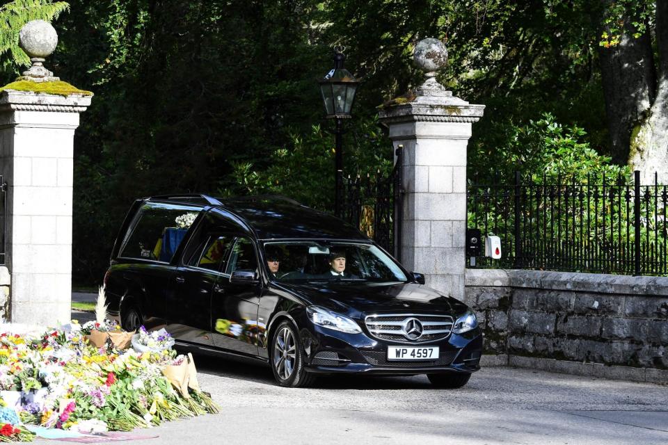 The hearse carrying the coffin of Queen Elizabeth II covered with the Royal Standard of Scotland and a flowers is driven away from Balmoral Castle in Ballater, on September 11, 2022. - Queen Elizabeth II's coffin will travel by road through Scottish towns and villages on Sunday as it begins its final journey from her beloved Scottish retreat of Balmoral. The Queen, who died on September 8, will be taken to the Palace of Holyrood House before lying at rest in St Giles' Cathedral, before travelling onwards to London for her funeral. (Photo by ANDY BUCHANAN / AFP) (Photo by ANDY BUCHANAN/AFP via Getty Images)