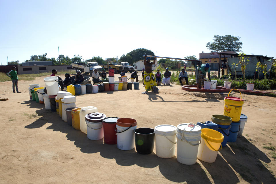 In this March, 31, 2020, photo, buckets are lined up as women fetch water in a suburb of Harare, Zimbabwe. For people around the world who are affected by war and poverty, the simple act of washing hands is a luxury, even during the coronavirus pandemic. In Zimbabwe, clean water is often saved for daily tasks like doing dishes and flushing toilets. (AP Photo/Tsvangirayi Mukwazhi)