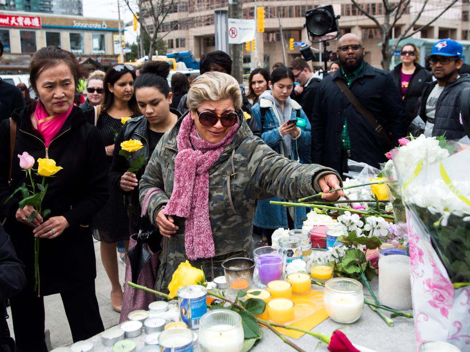 <p>Ozra Kenari, center, places flowers as she cries at a memorial for the victims along Yonge Street the day after a driver drove a van down sidewalks, striking pedestrians in his path, in Toronto, Tuesday, April 24, 2018. (Photo: Nathan Denette/The Canadian Press via AP) </p>