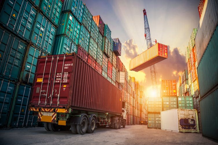 A crane loading shipping containers, lorry.