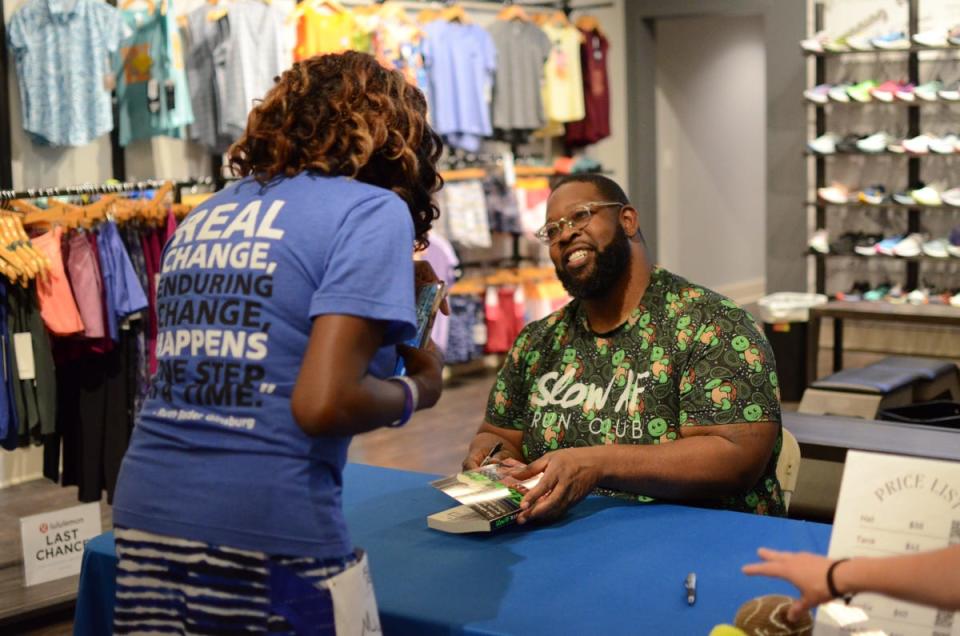 Martinus Evans, Detroit native and founder of Slow AF, interacts with visitor at book signing for recent publication “Slow AF Run Club: The Ultimate Guide for Anyone that Wants to Run”