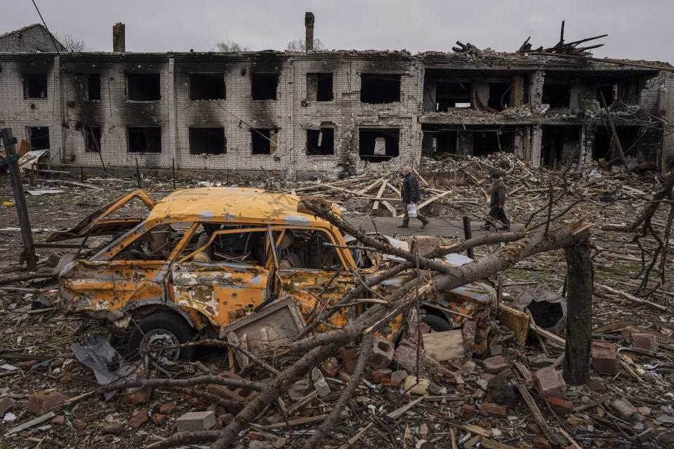 Men walk in a street destroyed by shelling in Chernihiv, Ukraine, Wednesday, April 13, 2022. (AP Photo/Evgeniy Maloletka)