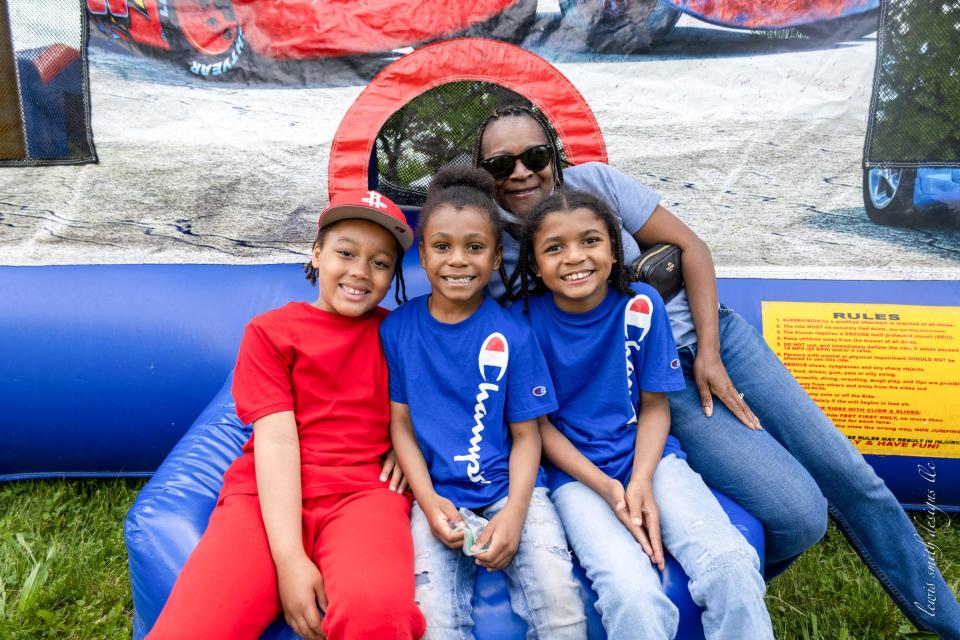 Attendees at a community festival in southwest Detroit posing in front of a bounce house.
