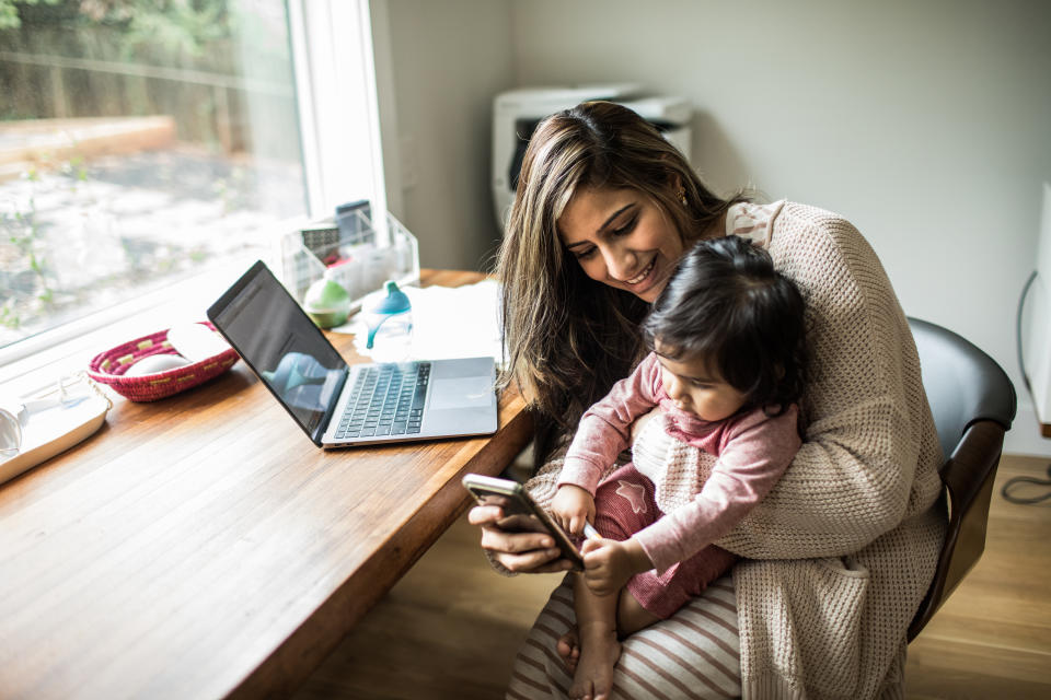 Mother multi-tasking with infant daughter in home office