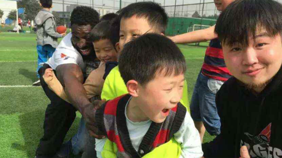 Wendell Brown teaches Chinese children how to play football during his tour in China. (AP)