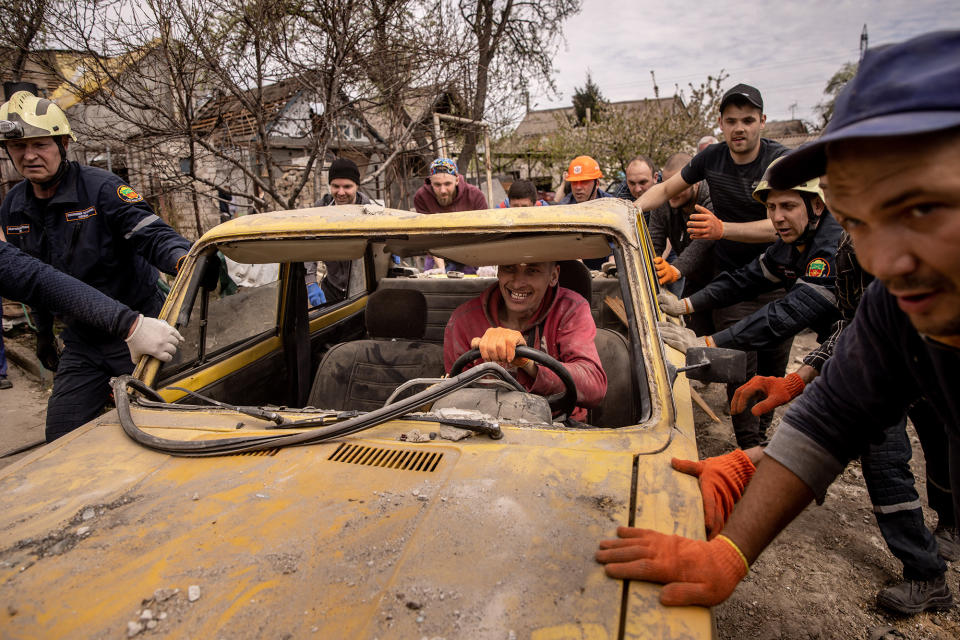 Residents and emergency services personnel push a damaged car from the driveway of a destroyed house during cleanup operations a day after a Russian attack in Zaporizhia, Ukraine, on April 29, 2022.