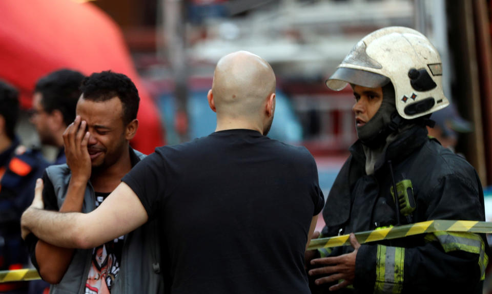 <p>Firefighter officers comfort a man near the site where a building collapsed in downtown Sao Paulo, Brazil May 1, 2018. (Photo: Leonardo Benassatto/Reuters) </p>