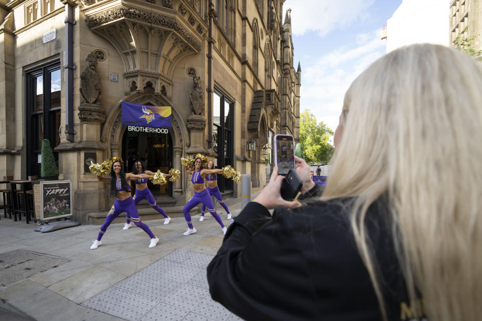 Cheerleaders for the The Minnesota Vikings record a TikTok video at a fan interaction event at The Brotherhood Of Pursuits And Pastimes sports bar in Manchester, England, Wednesday, Sept. 28, 2022. A half-dozen NFL teams are aggressively targeting fans in Britain now that they have new marketing rights in the country. They’re signing commercial deals and hiring local media personalities in bids to expand their fanbases and tap international revenue. (AP Photo/Jon Super)