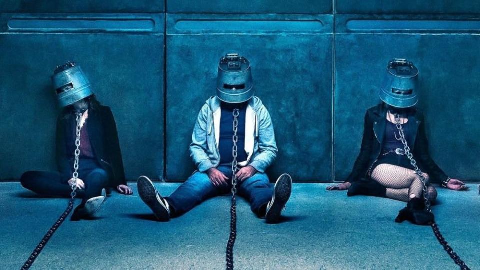 people are chained up with metal buckets on their heads in a scene from jigsaw