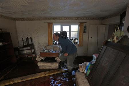 Phil Vize carries his pet cat through his flooded sitting room in the flooded Somerset village of Moorland February 15, 2014. British ministers will meet representatives of the insurance industry on Tuesday, February 18, who will brief them on their progress in dealing with victims of winter floods across southern England. REUTERS/Cathal McNaughton