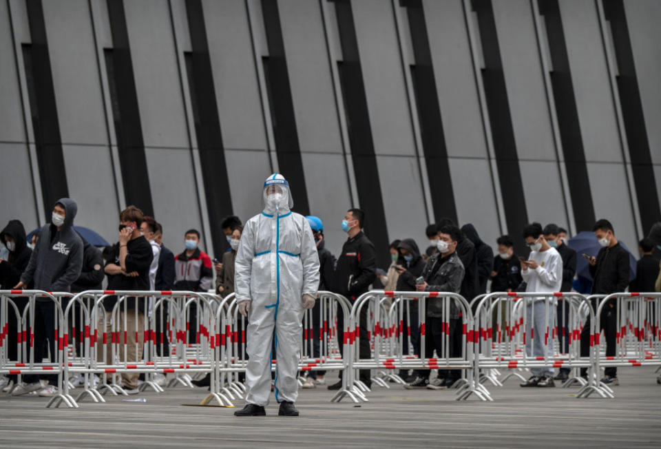 A health worker wears a protective suit as he directs people where to line up for nucleic acid tests to detect COVID-19 at a makeshift testing site in the Central Business District in Chaoyang on April 27, 2022 in Beijing, China.<span class="copyright">Kevin Frayer/Getty Images</span>