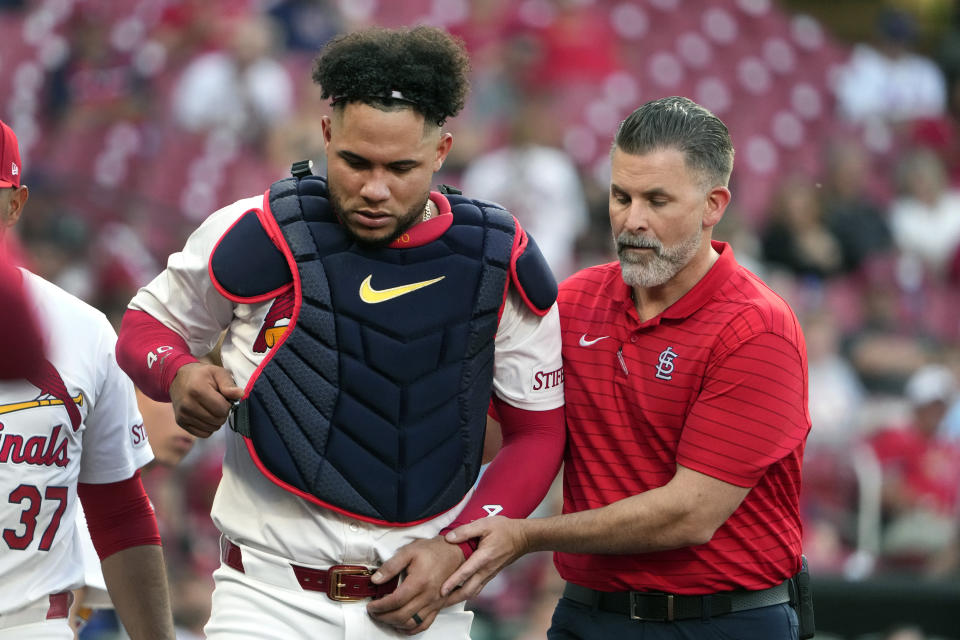 St. Louis Cardinals catcher Willson Contreras, left, is helped off the field by trainer Adam Olsen, right, after being injured during the second inning of a baseball game against the New York Mets Tuesday, May 7, 2024, in St. Louis. Contreras left the game. (AP Photo/Jeff Roberson)