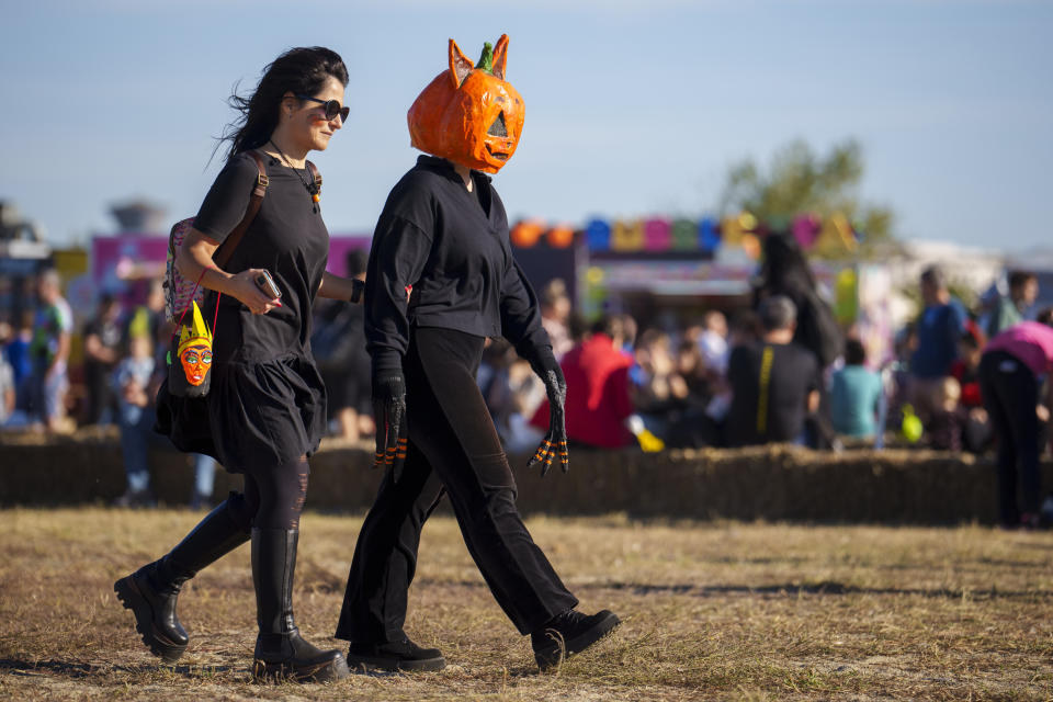 People wearing costumes walk at the West Side Hallo Fest, a Halloween festival in Bucharest, Romania, Saturday, Oct. 28, 2023. Tens of thousands streamed last weekend to Bucharest's Angels' Island peninsula for what was the biggest Halloween festival in the Eastern European nation since the fall of Communism. (AP Photo/Vadim Ghirda)