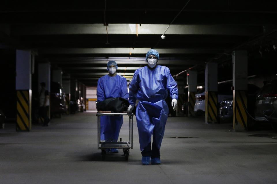 Healthcare workers transport to a morgue the body of a patient who died from COVID-19 at Clinicas Hospital in San Lorenzo, Paraguay, Wednesday, May 19, 2021. The Health Ministry reported that a record number of people died from COVID-19 on Tuesday, May 18. (AP Photo/Jorge Saenz)