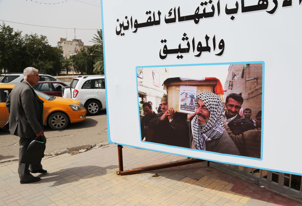 In this Tuesday, March 18, 2014 photo, an Iraqi man walks past an anti- terrorism billboard with Arabic that reads, "terrorists violate laws and agreements," in Baghdad, Iraq. Islamic militants who took over the Iraqi city of Fallujah are now trying to show they can run it, providing social services, policing the streets and implementing Shariah rulings in a bid to win the support of its Sunni Muslim population. (AP Photo/Karim Kadim)