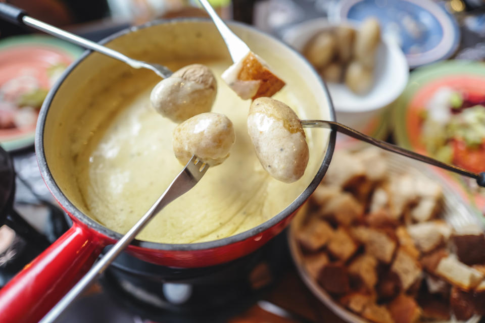 The famous authentic Swiss cheese fondue served in an earthenware pot, with cubed breads and potatoes  dipping into rich melted cheese, landmark of Switzerland.