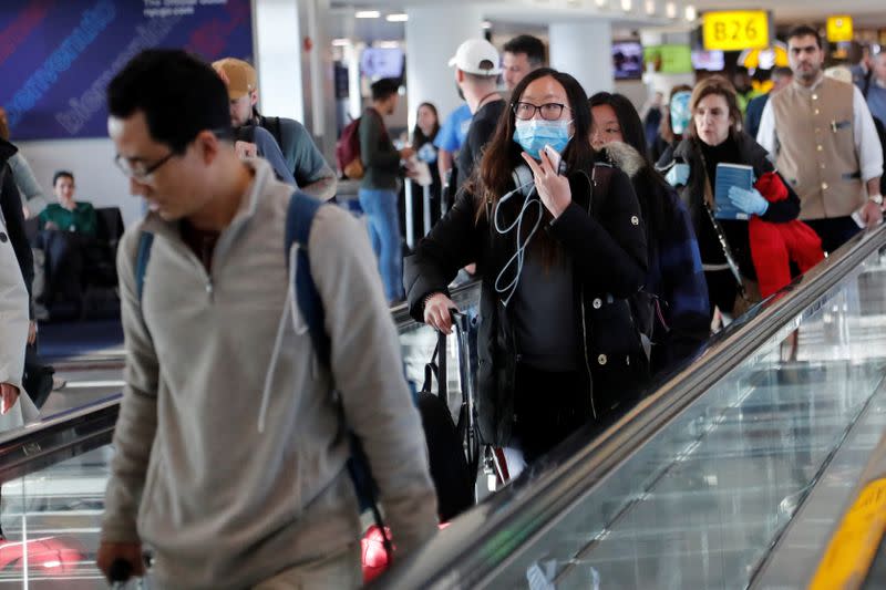 A woman walks with a face mask, after further cases of coronavirus were confirmed in New York, at JFK International Airport in New York