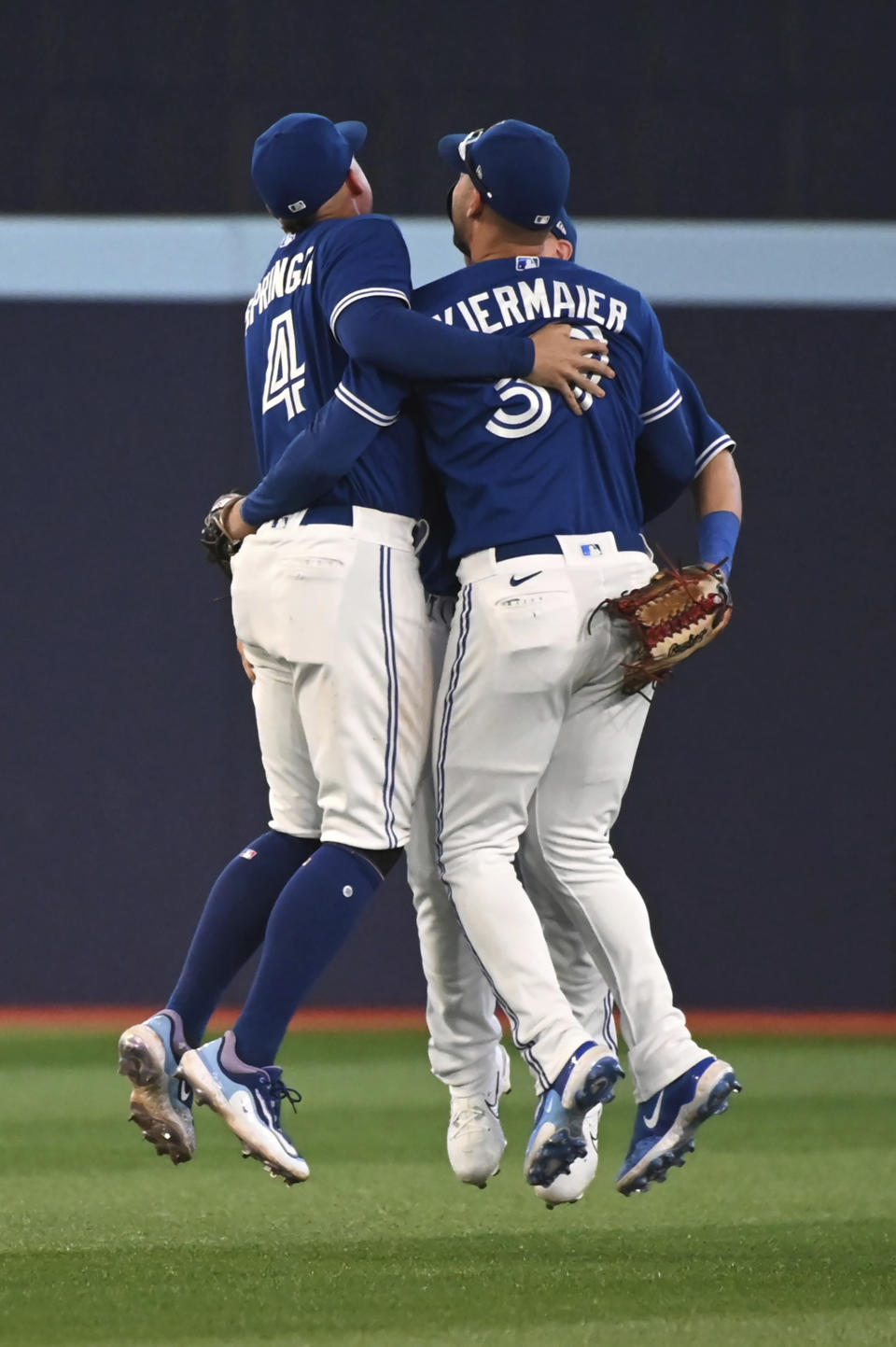 Toronto Blue Jays' George Springer (4), Daulton Varsho (25) and Kevin Kiermaier (39) celebrate the team's victory over the Oakland Athletics after a baseball game in Toronto, Saturday, June 24, 2023. (Jon Blacker/The Canadian Press via AP)
