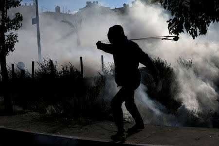 A Palestinian protester uses a sling to hurl stones towards Israeli troops during clashes at a protest against U.S. President Donald Trump's decision to recognize Jerusalem as the capital of Israel, near the Jewish settlement of Beit El, near the West Bank city of Ramallah December 7, 2017. REUTERS/Mohamad Torokman