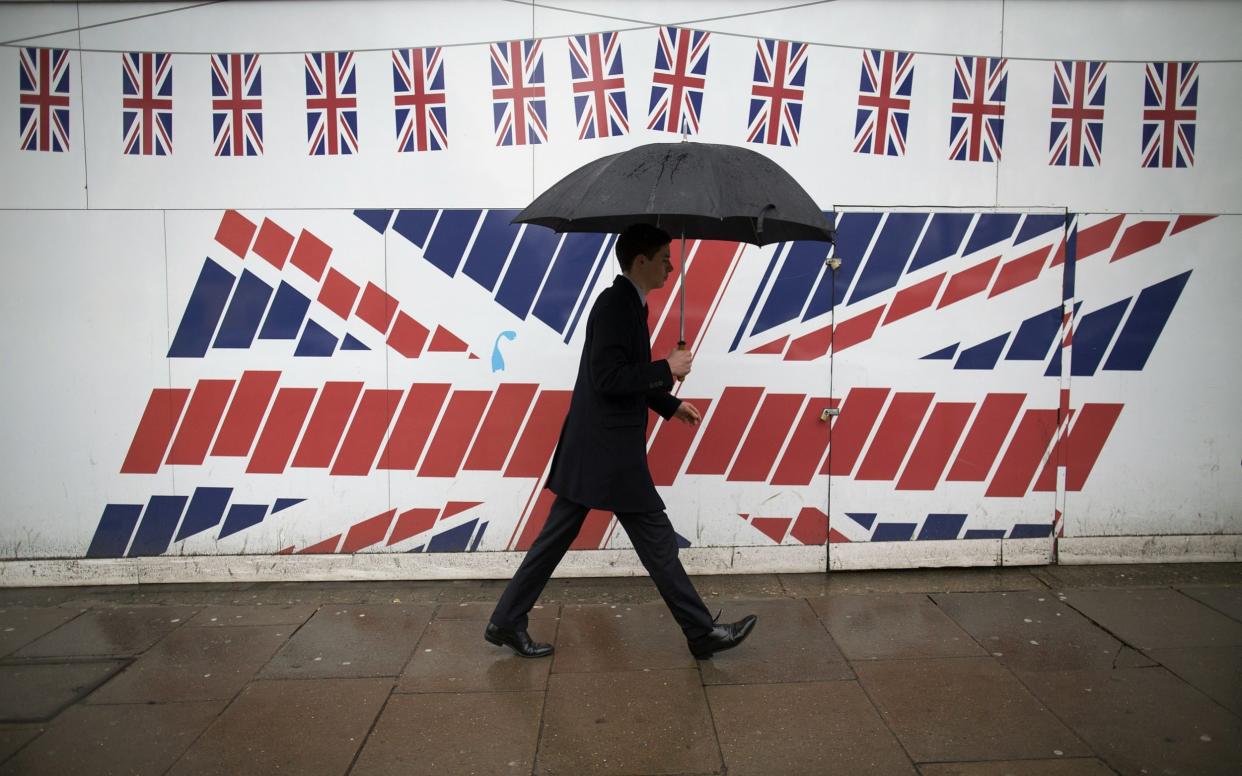 A pedestrian walks past a Union Jack flag - Simon Dawson /Bloomberg 