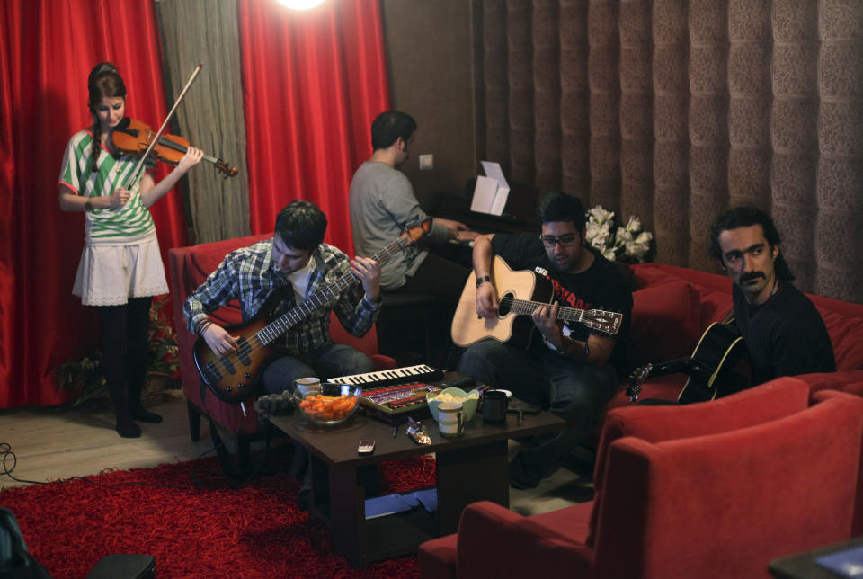 In this picture taken on Monday, Feb. 4, 2013, Nastaran Ghaffari, from left, Kamyar Shahdoust, Farbod Shirmohammad, Danial Izadi and Hamed Babaei, members of an Iranian band called "Accolade," practice at the house of one of the members in Tehran, Iran. Heavy metal guitarists jamming in basements. Headphone-wearing disc jockeys mixing beats. It’s an underground music scene that is flourishing in Iran, despite government restrictions. (AP Photo/Vahid Salemi)