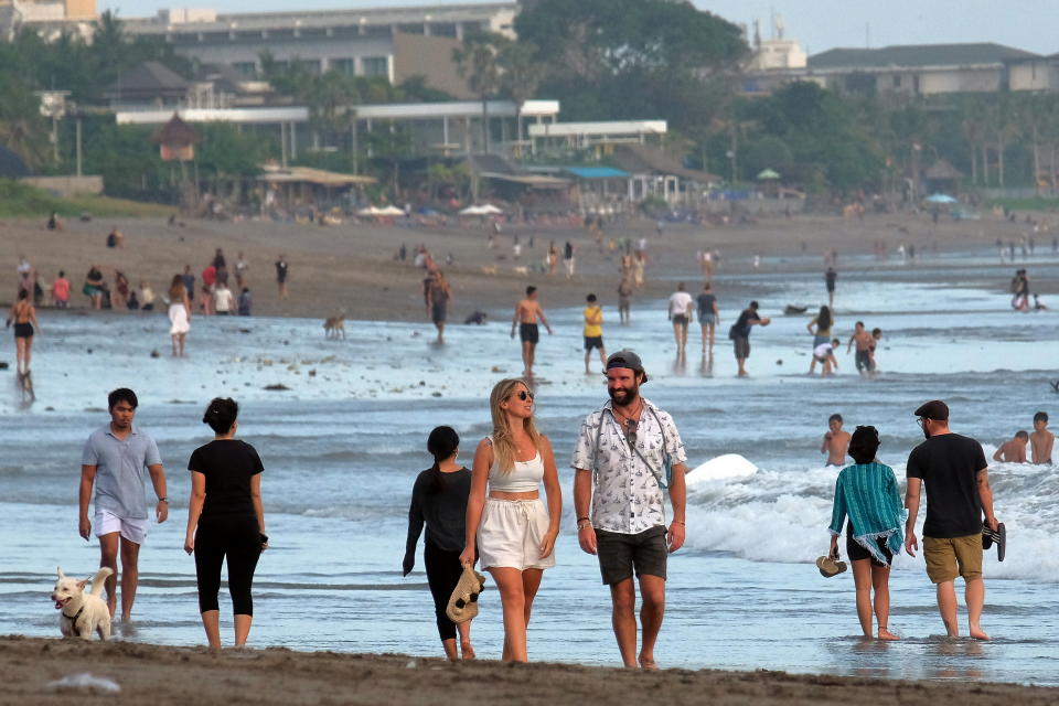 Tourists walk on a beach in Badung, Bali.