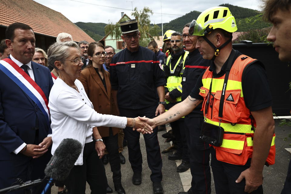 French Prime Minister Elisabeth Borne, 2nd left, shakes hands with a firefighter taking part in the rescue operations after a fire erupted at a holiday home for disabled people in Wintzenheim, France, Wednesday, Aug. 9, 2023. Eleven people have died after a fire ripped through a vacation home for adults with disabilities in eastern France. The deputy prosecutor of Colmar said 11 people who were sleeping on the upper floor and in a mezzanine area of the private accommodation were trapped by the fire, while five managed to escape. (Sebastien Bozon, Pool Photo via AP)